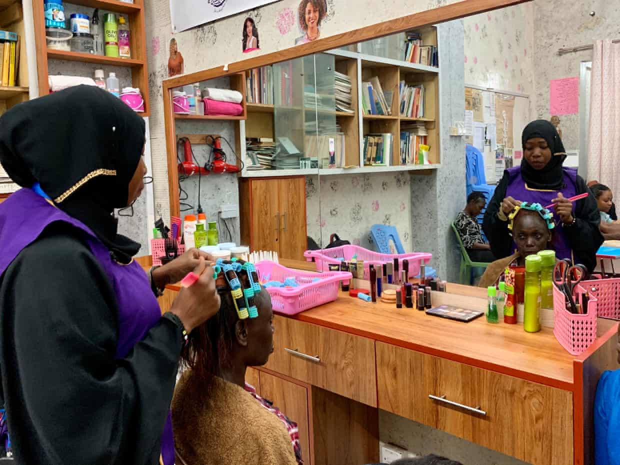 Woman does the hair of a customer at a beauty parlour in Kenya