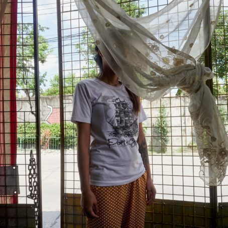 A young girl with her face hidden by curtains