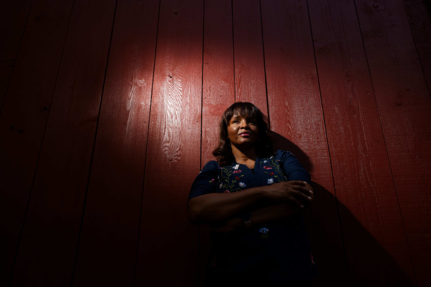 Photo of a woman leaning against a red barn