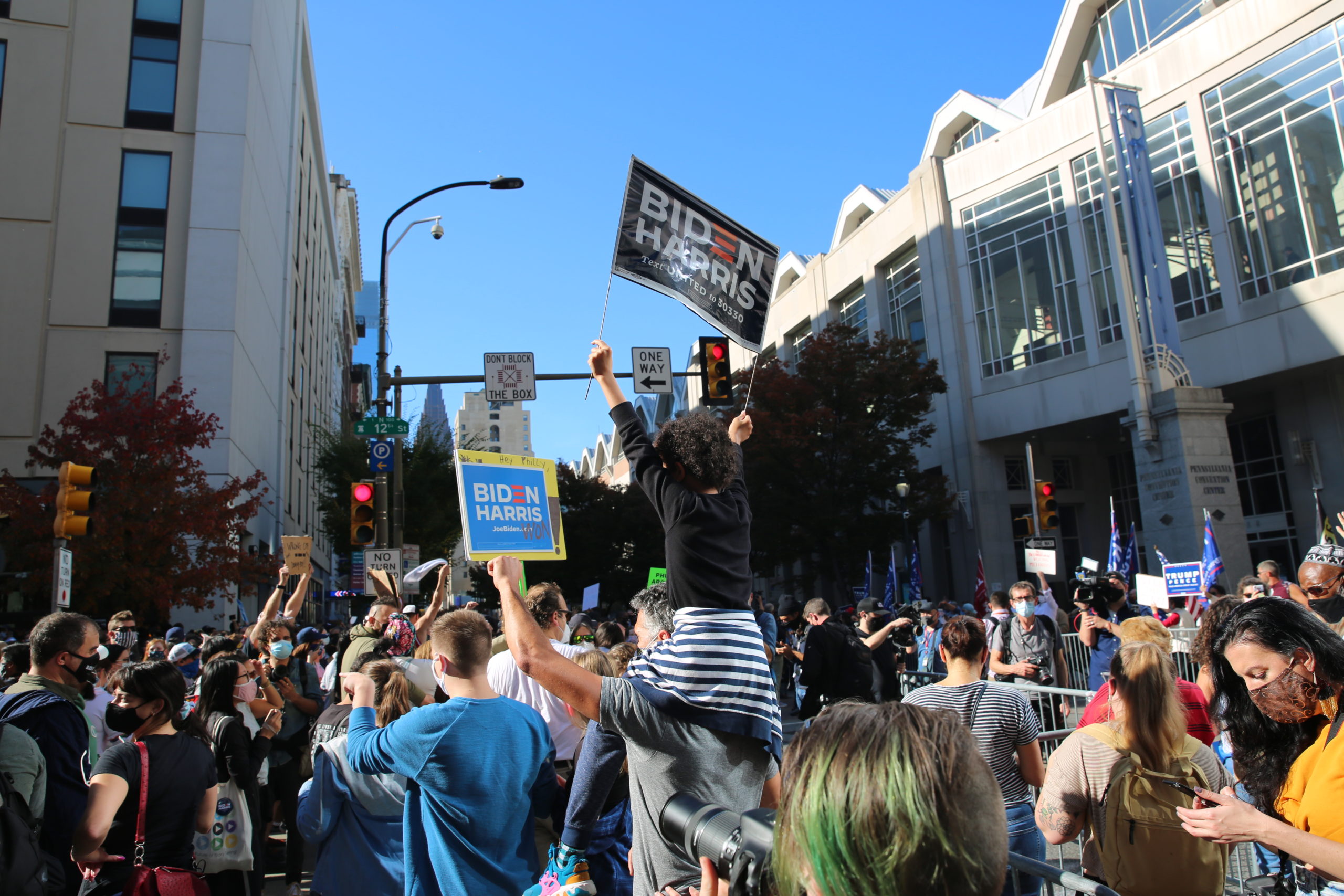 Little girl is sitting on a man's shoulders holding a sign