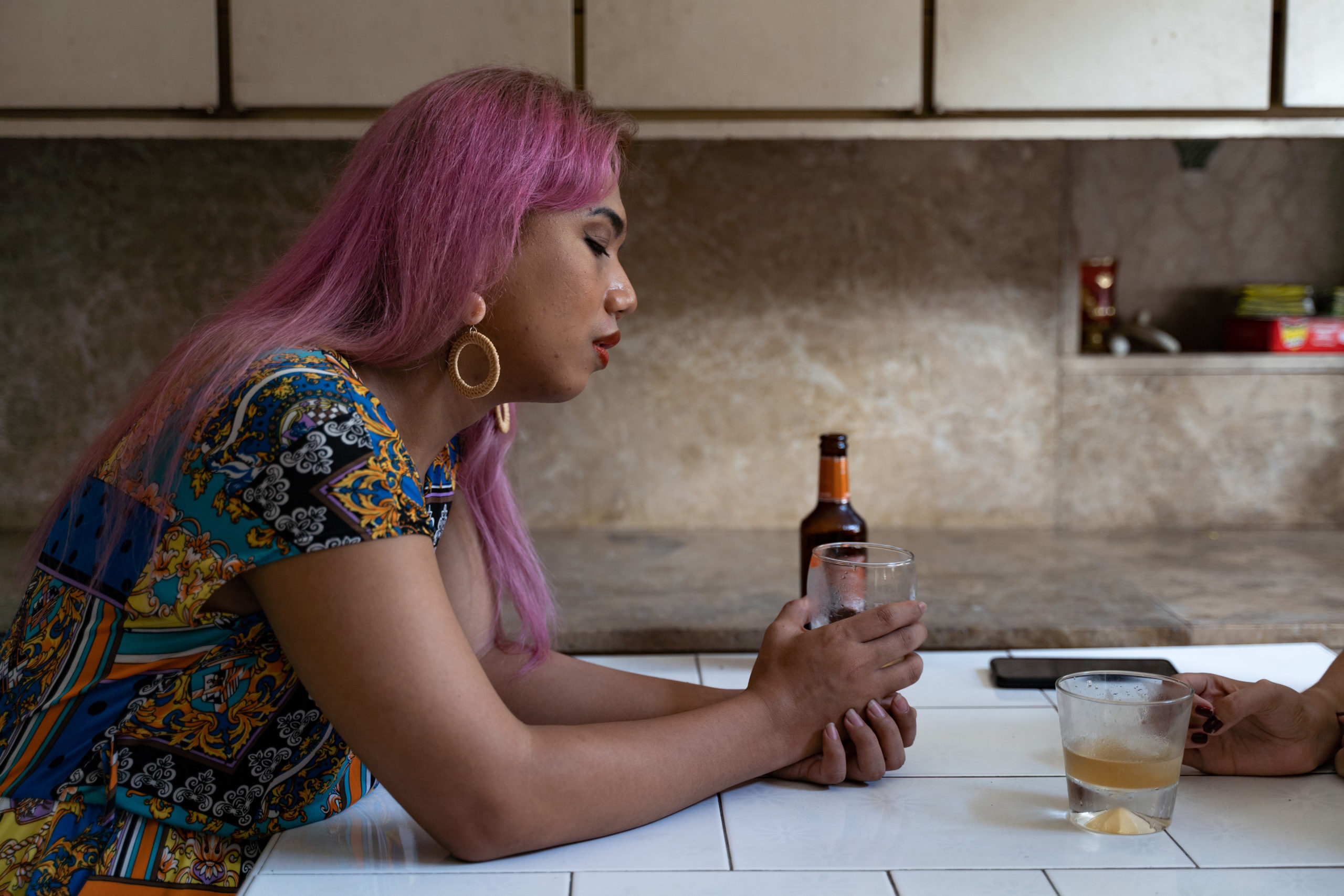 A photo of a woman seated at a table drinking with another person