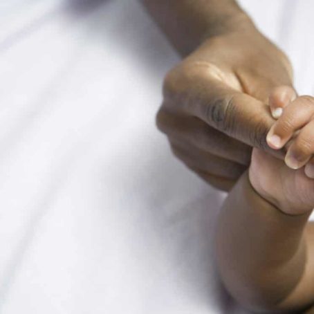 A photo of a baby holding a woman's finger