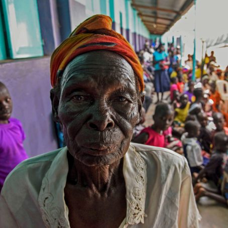 A photo portrait of a woman with a crowd of people seated in the background
