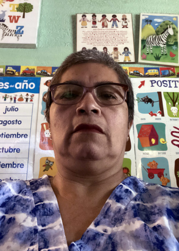 A portrait photo of a woman standing in front of educational posters