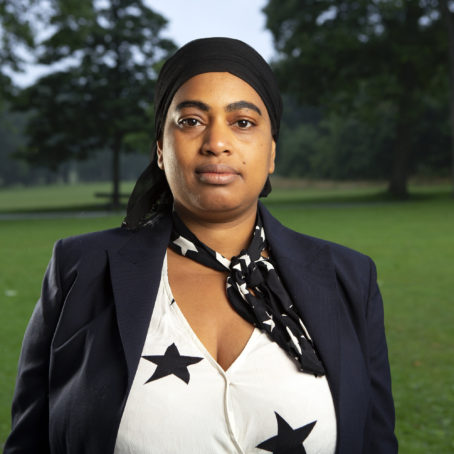 Photo of a woman with a head scarf and navy suit standing outside