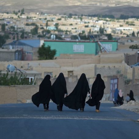 A photo of four women in burkas walking down a road