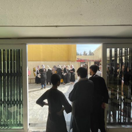 Photo of a group of women staging a protest as men stand in a doorway