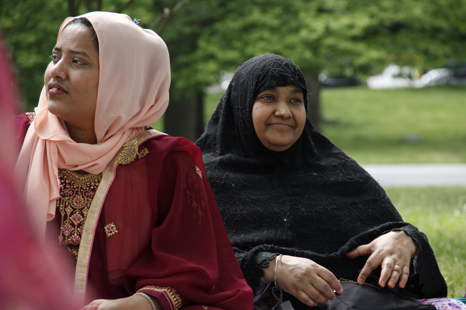A photo of two women seated in the grass at an outdoor gathering