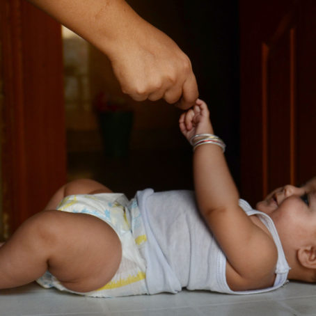 A photo of a baby holding an adult's finger