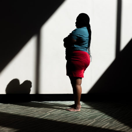 A photo of a woman standing to the side, in profile