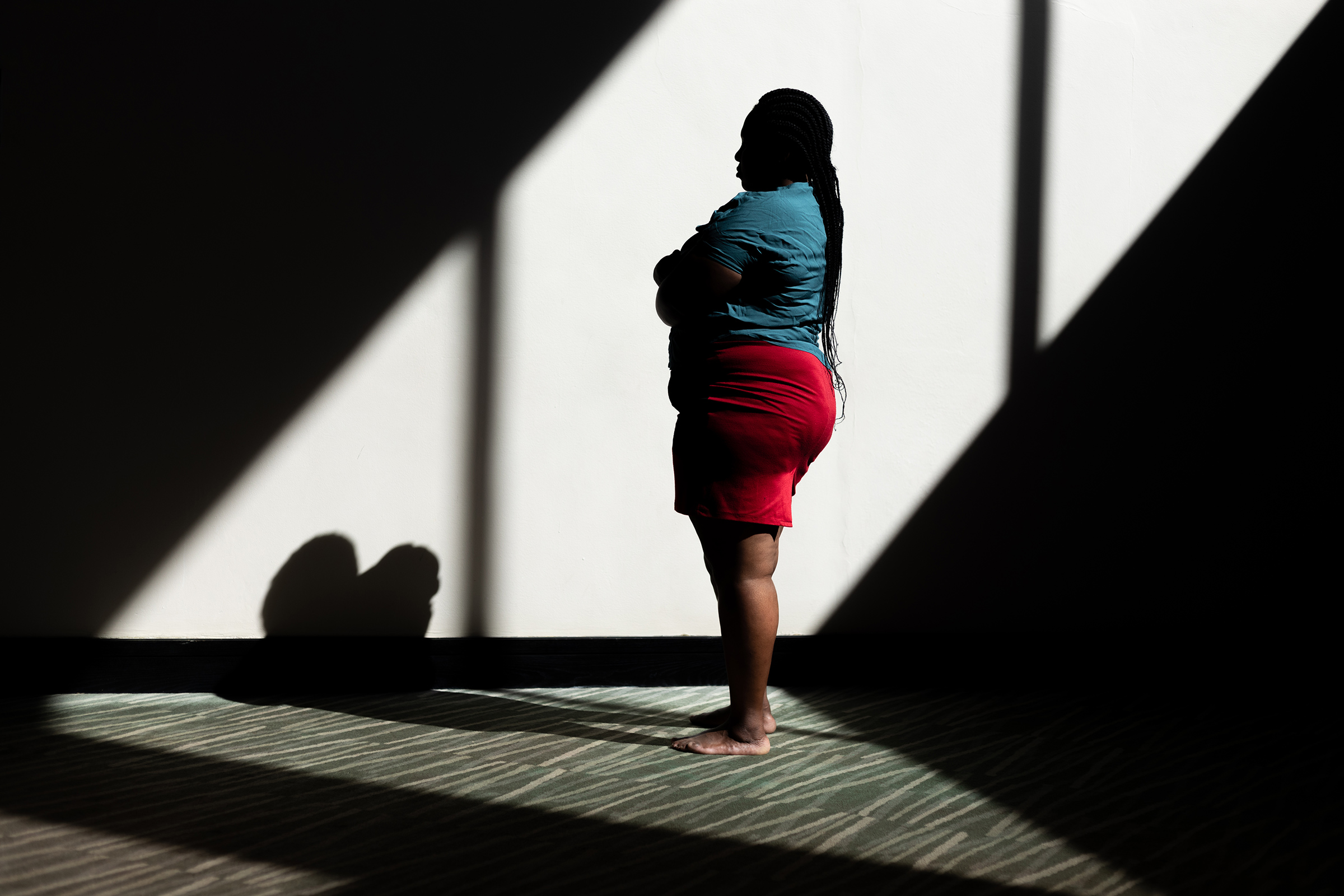 A photo of a woman standing to the side, in profile