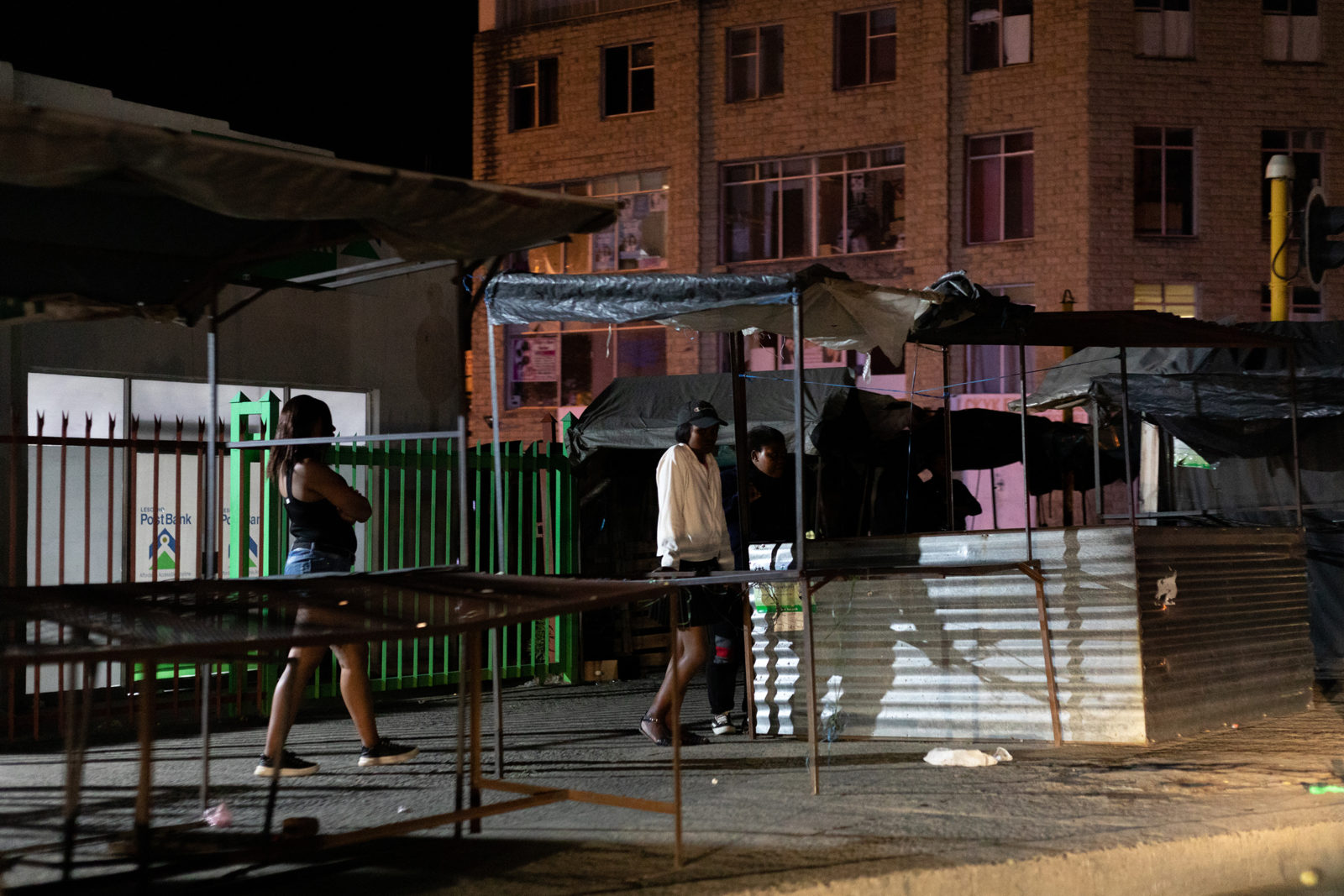 A photo of people walking along a city sidewalk at night
