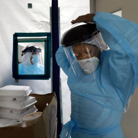 A photo of a nurse putting on a hazmat suit