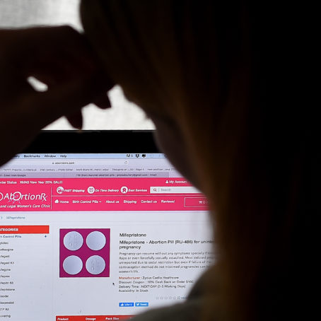 A photo with a person's silhouette looking at a laptop
