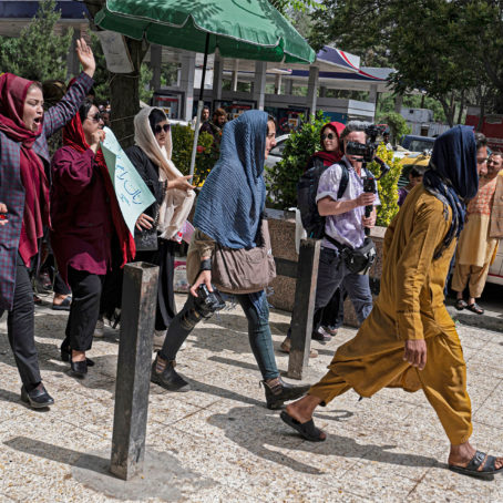 A photo of protesters holding signs and chanting
