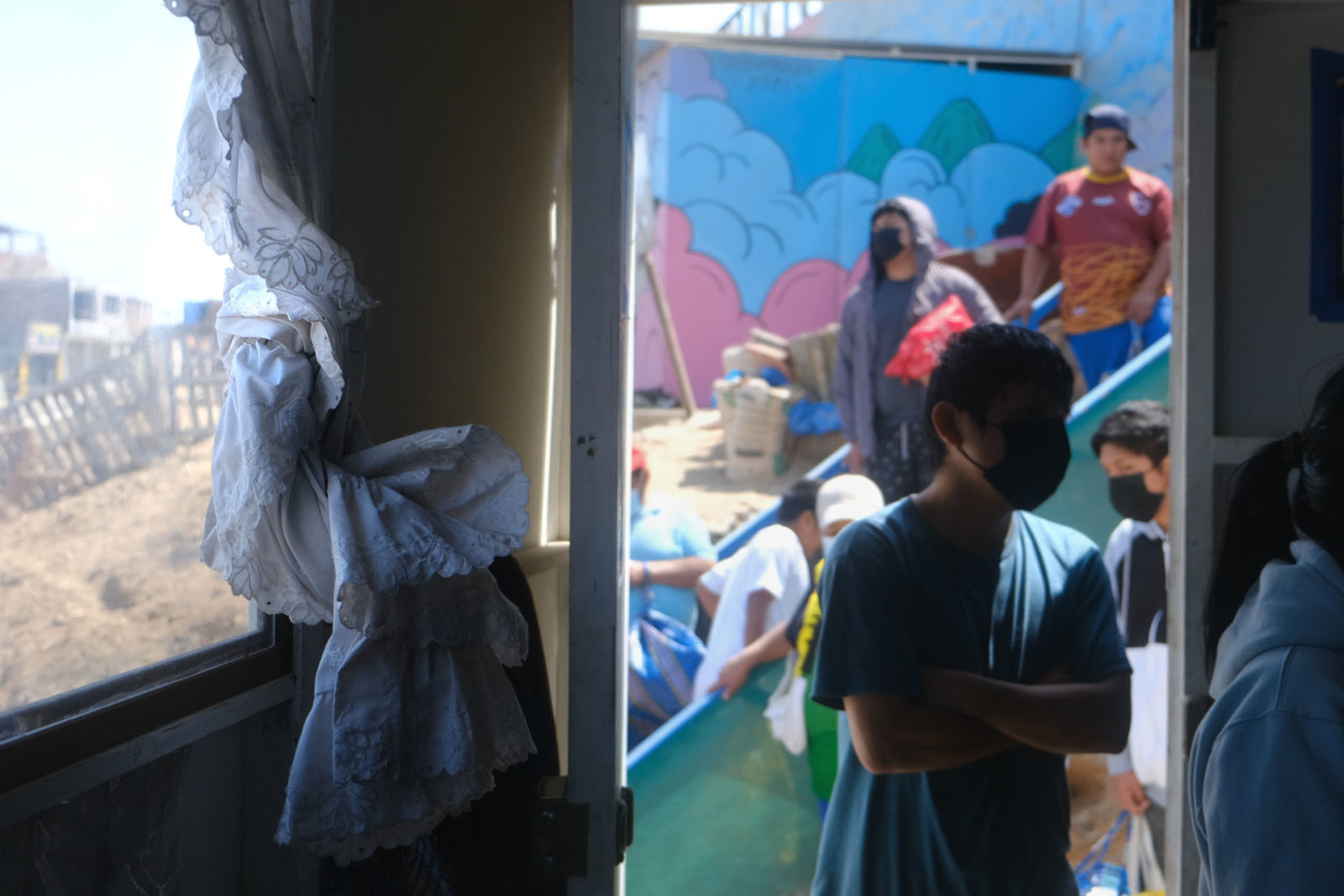 A photo of a person's silhouette standing in a doorway with a line of people in the background