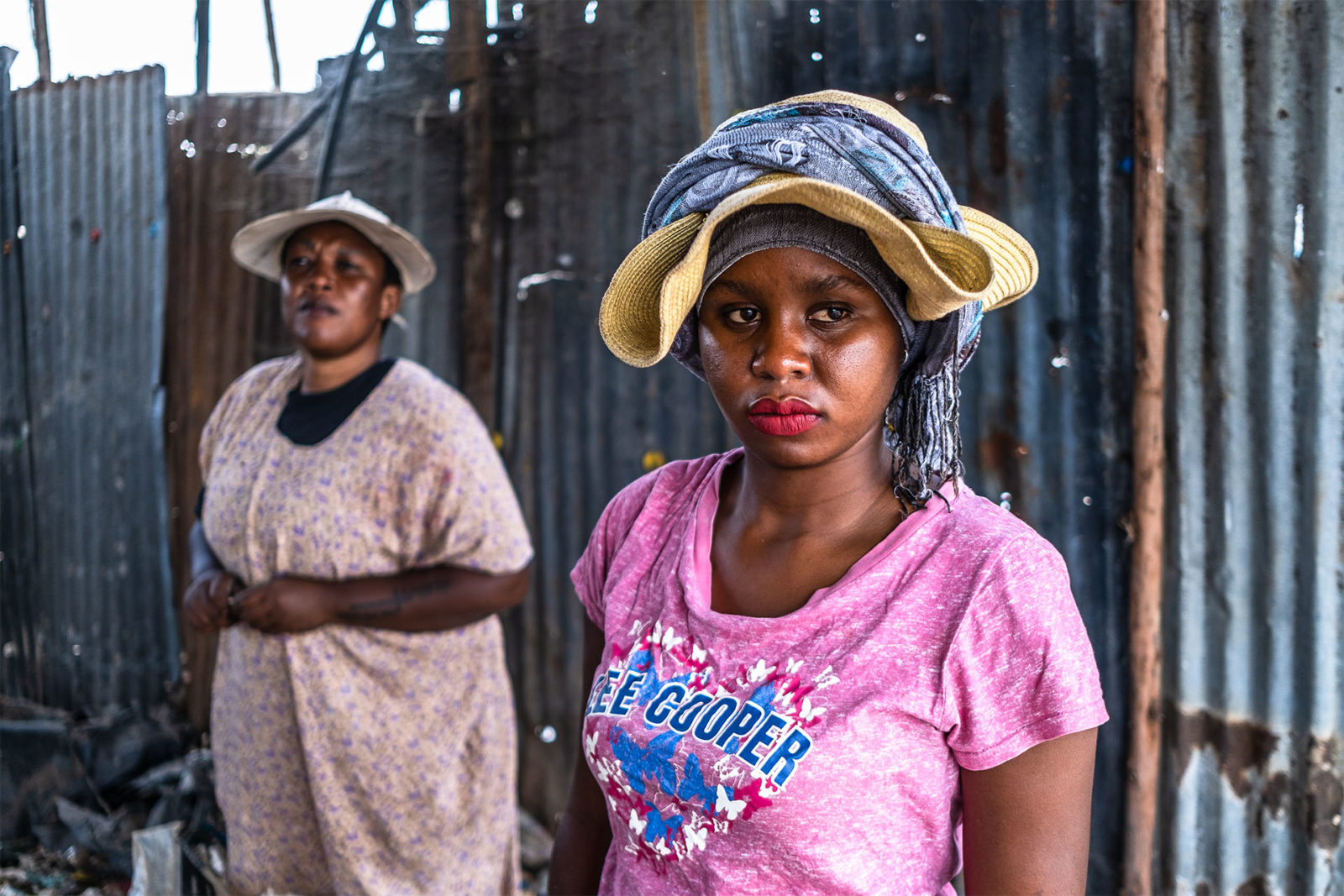 A photo of two women standing in front of a metal fence