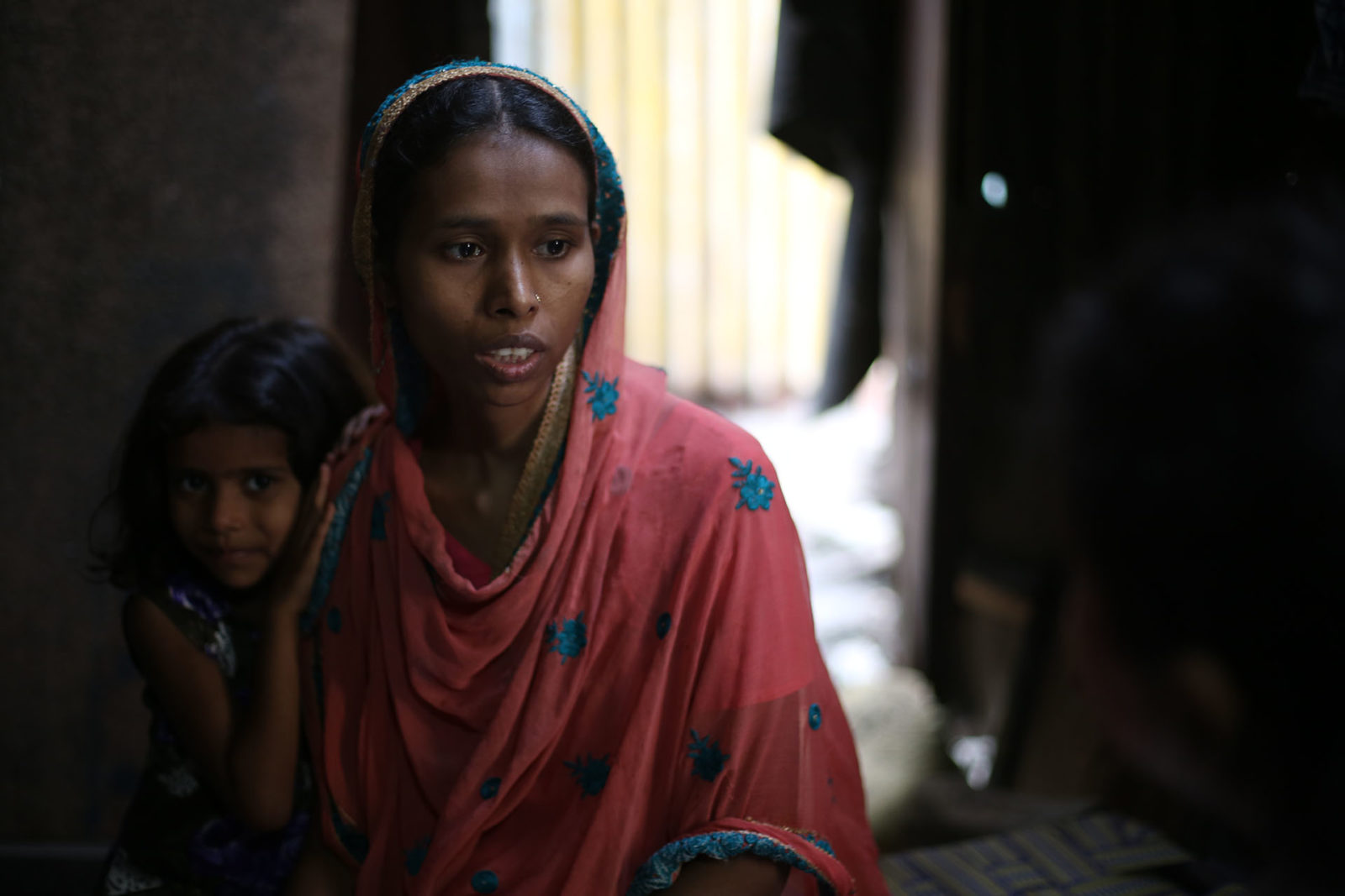 A photo of a woman with a child peeking from behind her