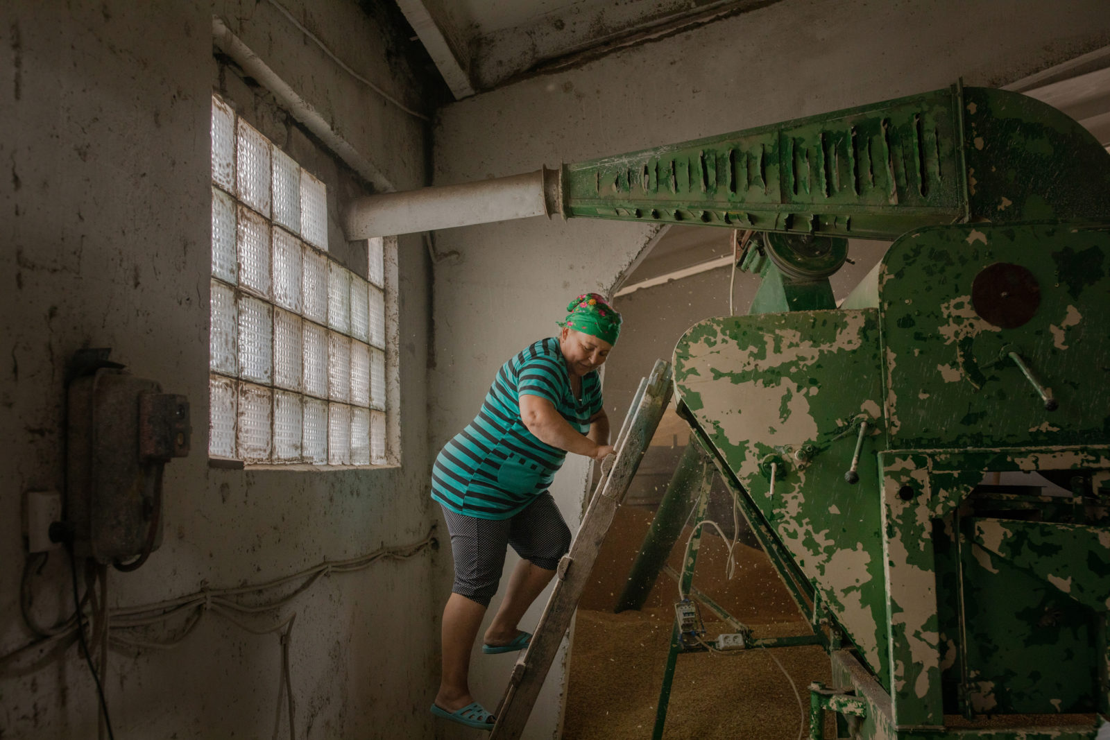 A woman climbs a ladder to a piece of farm equipment