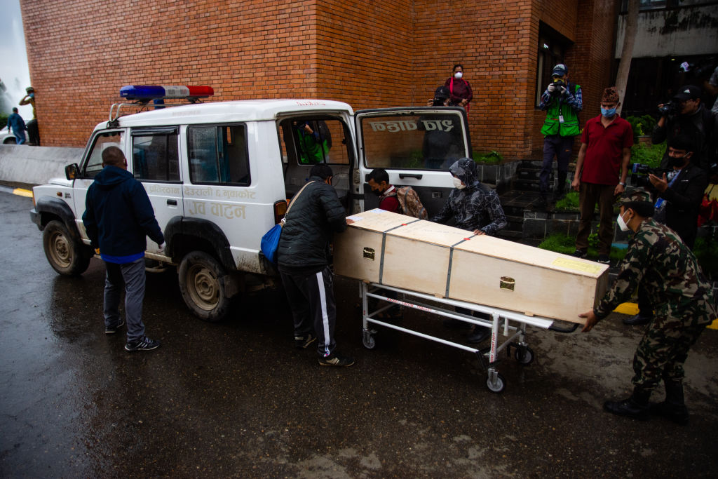 People carry a body in a coffin outside of an airport in Nepal.