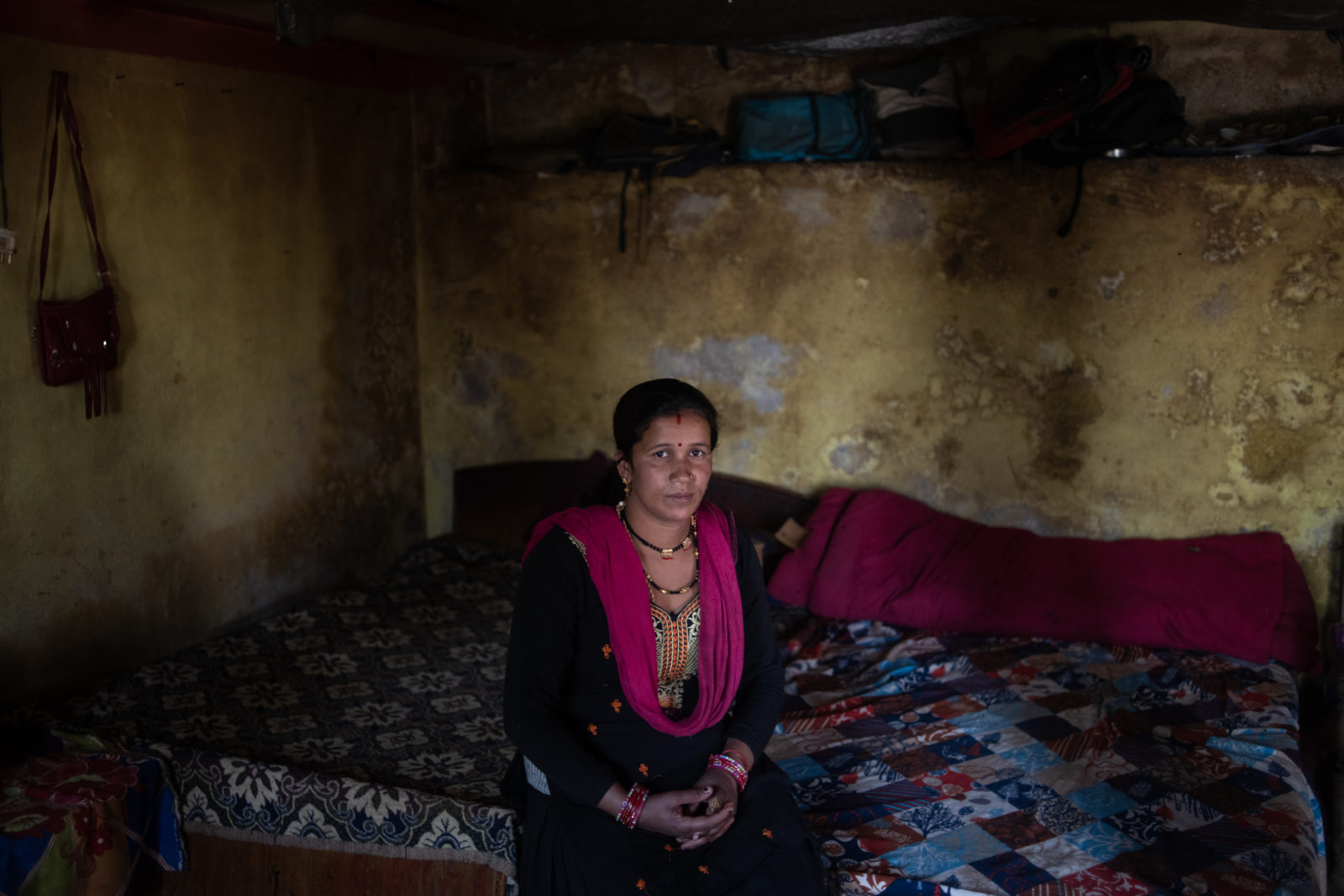 A woman sits on her bed.