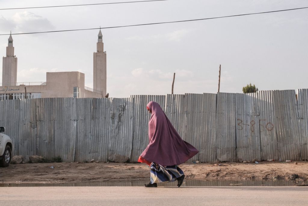A woman walks past a wooden fence in Somaliland