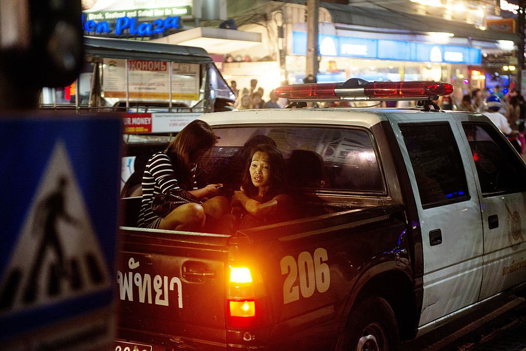 Two women sit in the back of a police truck.