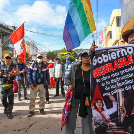 People stand in a street waving flag and shouting