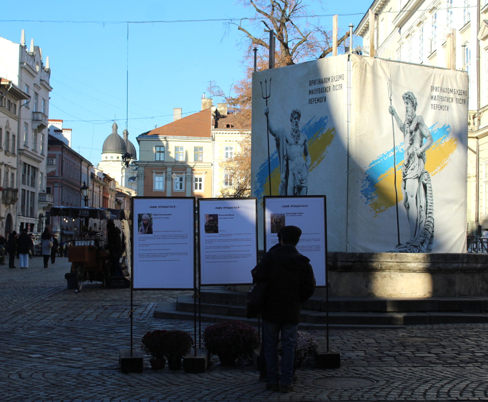 A person stands in front of a poster board with the names and faces of soldiers who died in the Ukraine-Russia War.