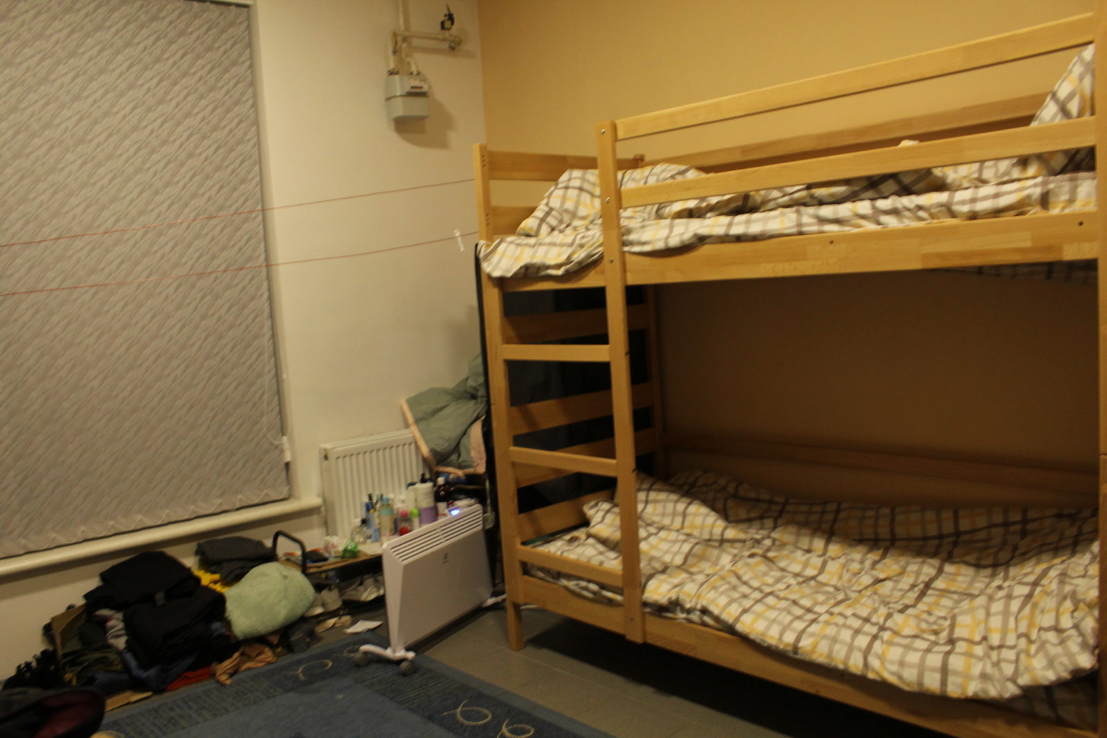 A brown bunkbed and a pile of items laying next to it on the floor.