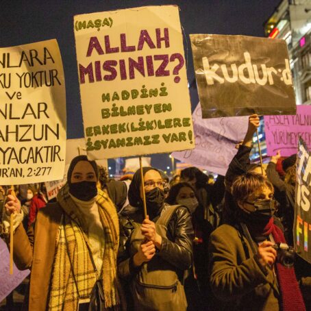 A group of women stand together holding signs.