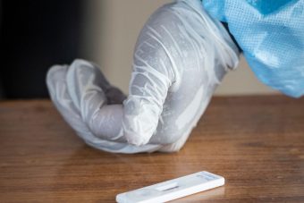 A health worker wearing a PPE kit monitors an antigen test kit after collecting swabs of asymptomatic passengers arriving from other states at railway station in Pune, India on April 23, 2021 in (Photo by Pratham Gokhale/Hindustan Times via Getty Images)