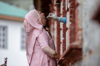 A photo of medical worker inserting a swab inside of a woman's mouth