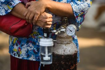 NEW DELHI, INDIA - APRIL 22:  A woman holds onto her personal oxygen cylinder at LNJP Hospital,  on April 22, 2021 in New Delhi, India. Delhi logged 26,219 fresh Covid-19 cases and 306 deaths due to the Covid on Thursday amid a growing clamour for oxygen and hospital beds in the city. The national capital's cumulative tally rose to 9,56,348 and the death toll stood at 13,193, according to health bulletin. (Photo by Amal KS/Hindustan Times via Getty Images)
